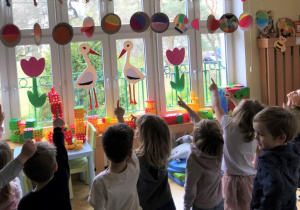 Dzieci wskazują palcem planety zrobione z kolorowego papieru